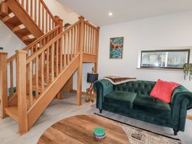 A living room with a green sofa and wooden stairs at Barn 2