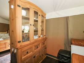 A hutch with dishes and glasses in a tent at Hedgerow in Bewdley