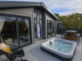 An outdoor terrace with a hot tub and dining table at Lakewood Retreat Woodhall Spa