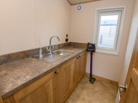 A utility room with a sink and storage cabinets at Lakewood Retreat in Woodhall Spa