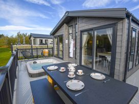A deck with a table set for tea and a hot tub at Lakewood Retreat in Woodhall Spa