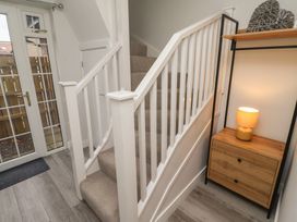 A hallway with a staircase and a console table at Nobles Nook in Seahouses