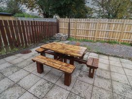 A garden with a wooden table and benches at Nobles Nook in Seahouses