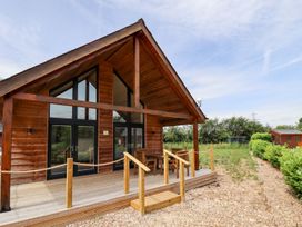 A wood cabin with a deck and seating area at Lodge 12 in South Hykeham