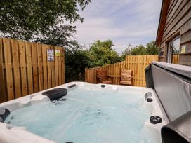 A hot tub with wooden chairs and a fence at Lodge 12 South Hykeham