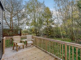 A deck with wooden chairs overlooking trees at Somersby (Pet) in Louth