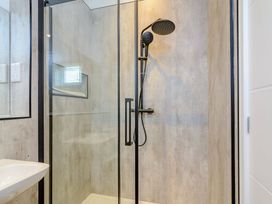 A shower with glass partition and sink in a bathroom at The Woodnewton in Wansford