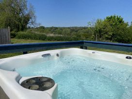 A hot tub with water and trees in the background at The Cow Shed in Bishopswood