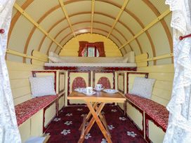 A main room with a table and seating at The Bowtop Gypsy Caravan in Eye