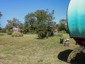 An outdoor area with a caravan and trees at The Bowtop Gypsy Caravan in Eye