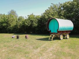 A caravan on grass with a stool and pot at The Bowtop Gypsy Caravan in Eye