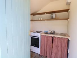 A kitchen with a stove, sink, and shelves at The Bowtop Gypsy Caravan in Eye