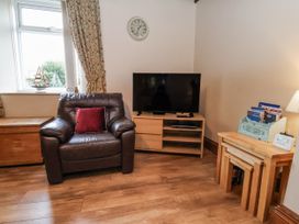 A living room with an armchair and a television at 2 High Stakesby Cottages in Whitby