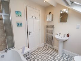 A bathroom with a bathtub, shower, sink, and towel rail at 2 High Stakesby Cottages in Whitby