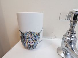 A mug with a highland cow illustration next to a sink at 2 High Stakesby Cottages in Whitby