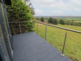 An outdoor deck area with railing and view of hills at John's Folly