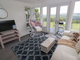 A living room with a hanging chair and television at John's Folly