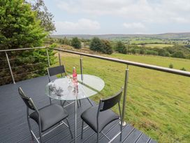 An outdoor seating area with chairs and a table overlooking a grassy landscape at John's Folly