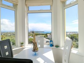 A dining area with a table and chairs overlooking the landscape at 19 Cliff Apartments in Trearddur Bay