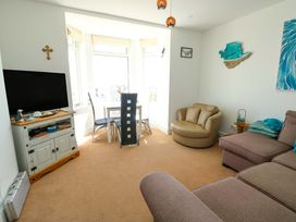 A living room with a television and dining area at 19 Cliff Apartments in Trearddur Bay