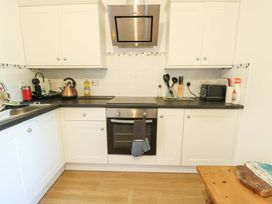 A kitchen with cabinets, sink, stove, and appliance at 19 Cliff Apartments Trearddur Bay