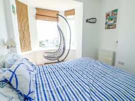 A bedroom with a bed and a hanging chair at 19 Cliff Apartments in Trearddur Bay