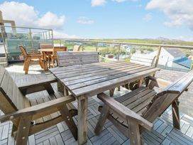 An outdoor seating area with wooden furniture and views at 19 Cliff Apartments in Trearddur Bay