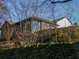 An exterior view of a house with trees and a stone wall at The Old Bunkhouse in Grasmere