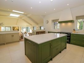 A kitchen with a green island and bar stools at The Old Bunkhouse in Grasmere