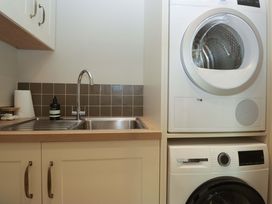 A laundry room with a sink and stacked washer and dryer at The Old Bunkhouse in Grasmere