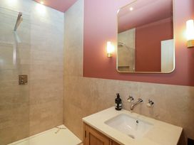 A bathroom with a shower, sink, and mirror at The Old Bunkhouse in Grasmere