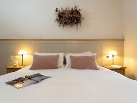 A bedroom with a bed, bedside table, lamp, and decorative wall piece at The Old Bunkhouse in Grasmere