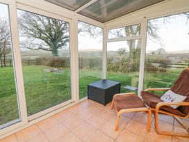 A conservatory with chairs and a view of the garden at Court House Farmhouse in Charmouth