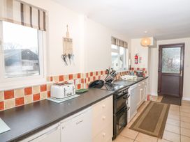A kitchen with various appliances and a window at Court House Farmhouse, Charmouth