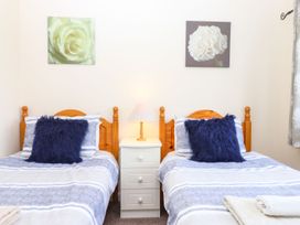 A bedroom with two beds and a lamp on a nightstand at Court House Farmhouse in Charmouth