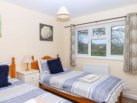 Two single beds with a bedside table and window at Court House Farmhouse, Charmouth
