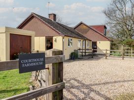 A farmhouse exterior with a driveway and fence at Court House Farmhouse in Charmouth