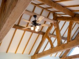 A ceiling fan with light bulbs and wooden beams at Nature's Lodge in Cookley