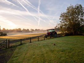 A tractor near a fence on a grassy field at Nature's Lodge in Cookley