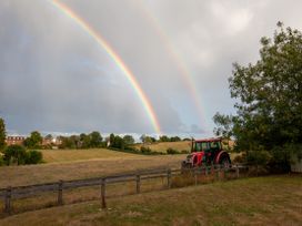 A tractor near a fence under a rainbow at Nature's Lodge in Cookley