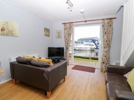 A living room with a television and a view of the water at Cotman Cottage Hoveton & Wroxham
