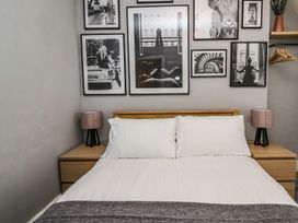 A bedroom with a bed, nightstand, lamp, and wall photo frames at 6 Upperfield Street in Dolgellau