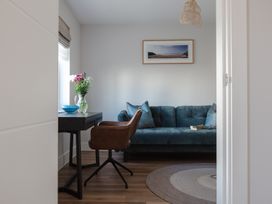 A living room with a sofa, chair, and a vase with flowers at Polview in Newquay