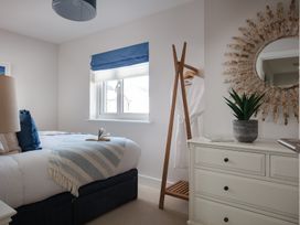 A bedroom with a bed, dresser, and plant at Polview in Newquay