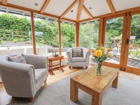 A conservatory with armchairs and a table at Bobbin Mill Cottage in Ulverston