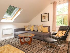 A living room with a sofa, table, and armchair at Bobbin Mill Cottage in Ulverston