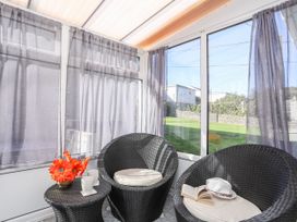 A conservatory with two armchairs and a coffee table at Gelli - Morfa Nefyn