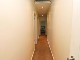 A hallway with doors and carpet leading to a bedroom at Gelli - Morfa Nefyn in Morfa Nefyn