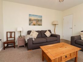 A living room with a sofa, coffee table and lamp at Gelli - Morfa Nefyn