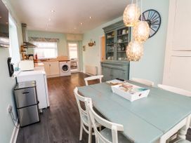 A kitchen with a dining table and appliances at Gelli - Morfa Nefyn
